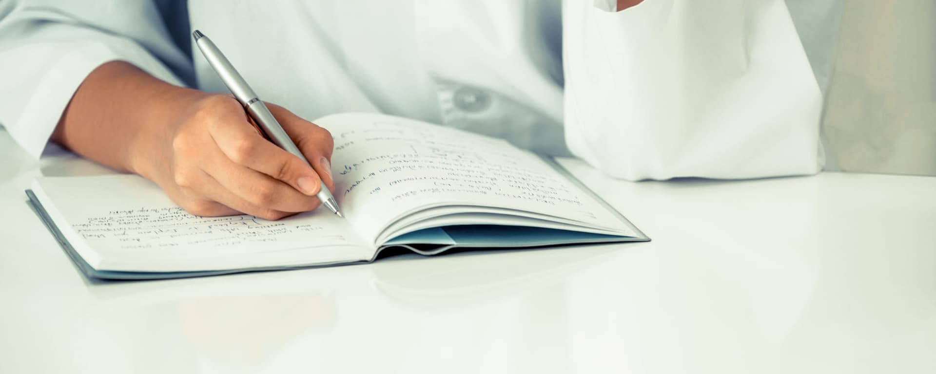 Manos de un médico escribiendo en un cuaderno