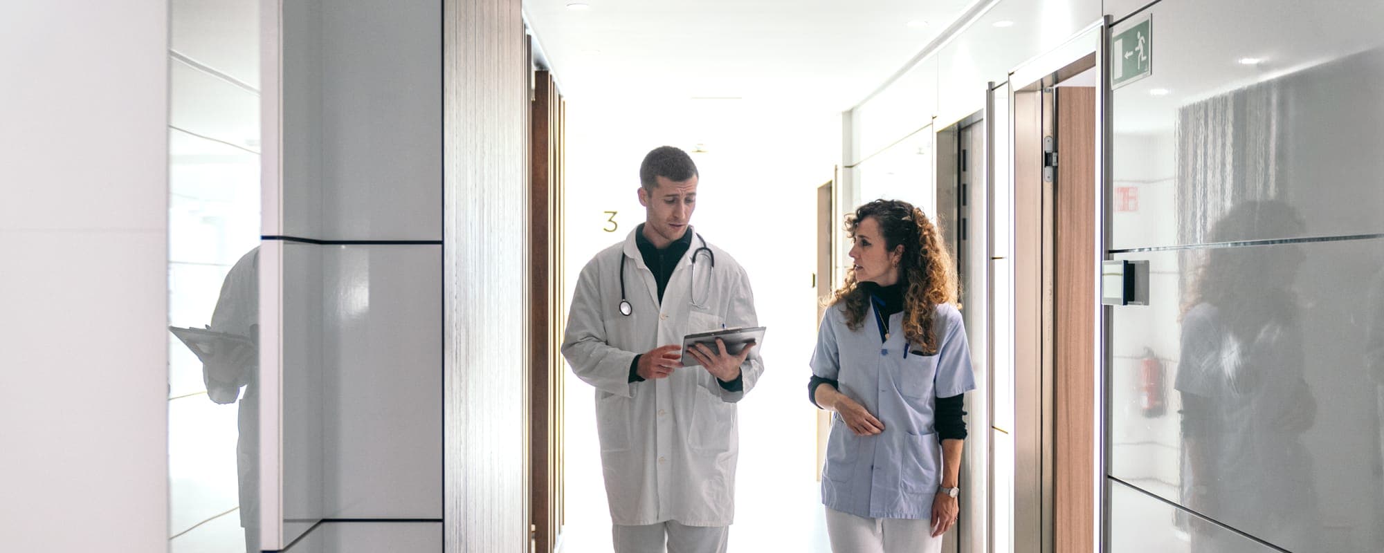 Médico y enfermera revisando una ficha en el pasillo del centro