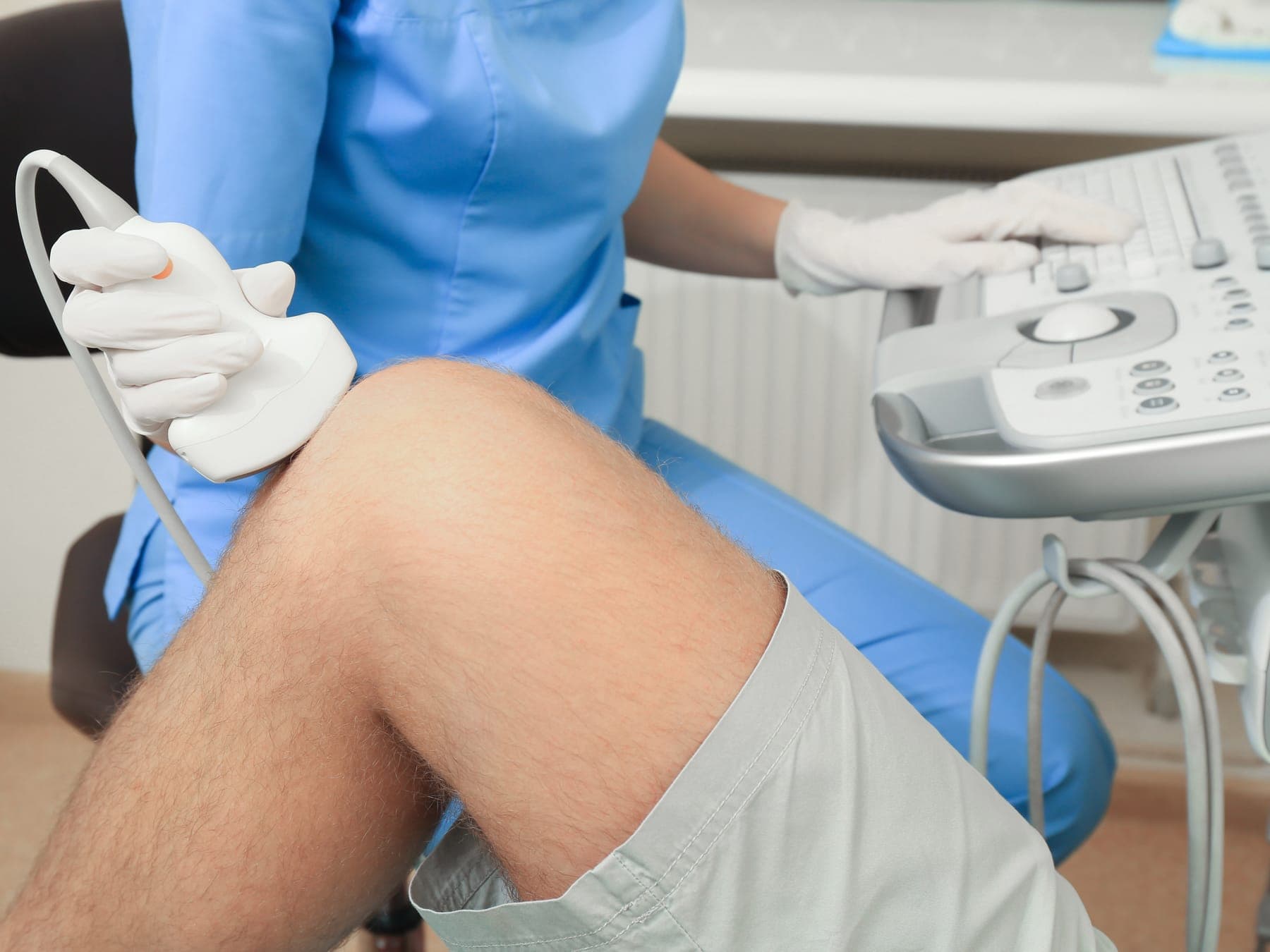 Profesional realizando una ecografía de rodilla con el transductor apoyado sobre la articulación