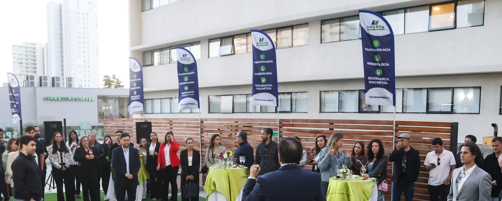 Equipo y invitados de SportsMD en la terraza del centro, junto a los pendones de la clínica