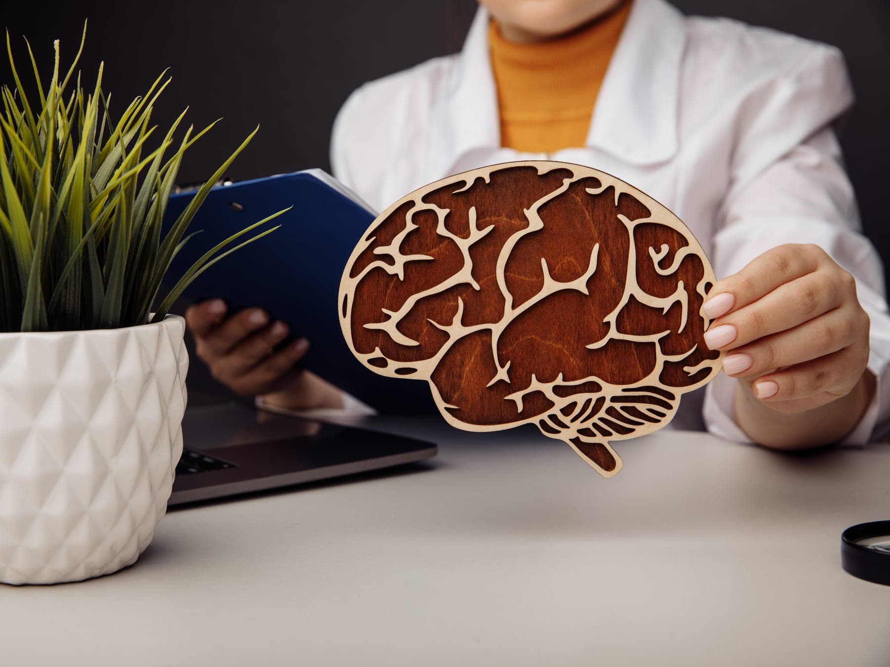 Psicóloga sosteniendo una figura de un cerebro sobre su escritorio