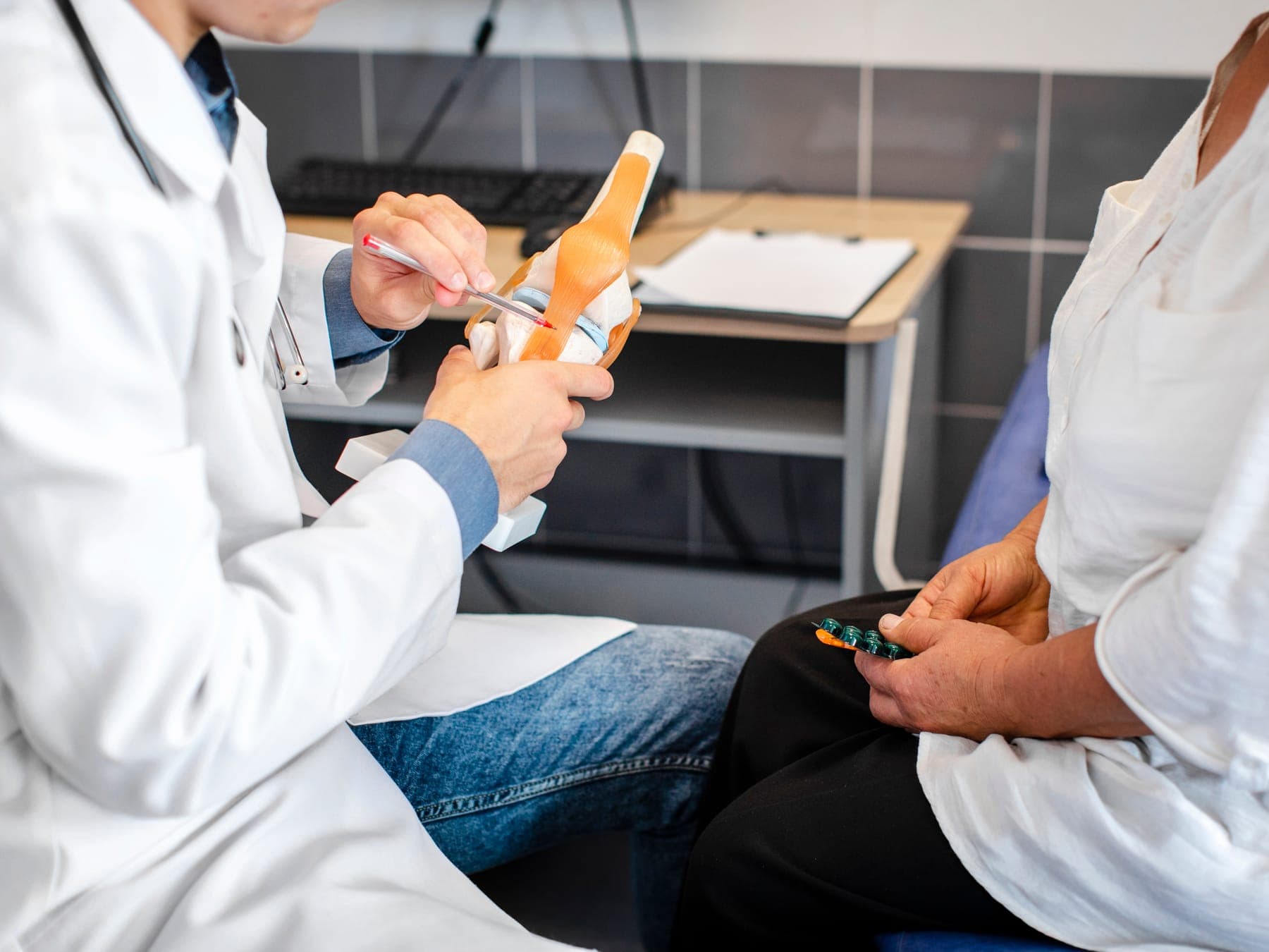 Traumatólogo explicando una lesión con un modelo anatómico de rodilla
